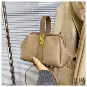 Close-up of a dark beige leather doctor bag featuring a golden twist-lock and top handle