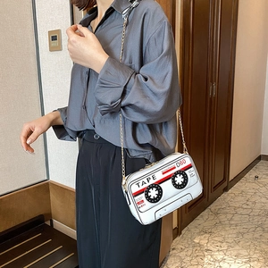 Model showing retro cassette tape crossbody bag with a gold chain strap on shoulder