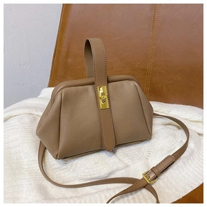 Detail of the litchi pattern leather and gold metal clasp on the brown shell bag