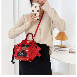 Detail of red crocodile texture handbag with chic lady graphic and pearl earrings