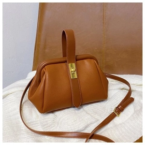 Detail of brown litchi leather texture and golden metal clasp on a vintage shell bag