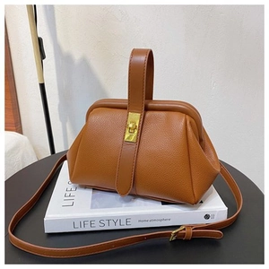 Detailed close-up of brown textured leather shell bag with gold lock and top handle