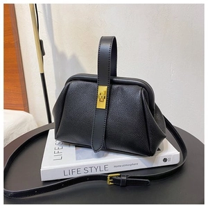 Detail of black pebbled leather doctor bag with gold metal lock and shoulder strap