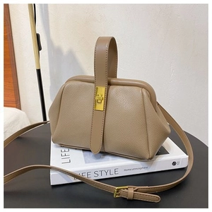 Detail of beige lychee pattern leather handbag with wide top handle and metal buckle