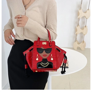 Detail of red croc-embossed handbag featuring pop art lady illustration and metal chain