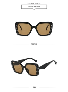 Close-up of square black sunglasses with decorative silver rivets and brown lenses