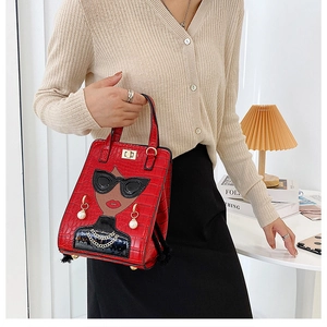Detail of red croc-embossed handbag featuring a girl with sunglasses and pearl accents