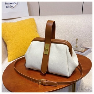 Detail of white lychee pattern shell bag with caramel leather handle and gold lock
