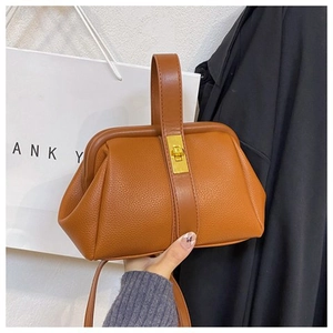 Detailed view of brown litchi pattern shell bag with vintage gold metal twist lock buckle
