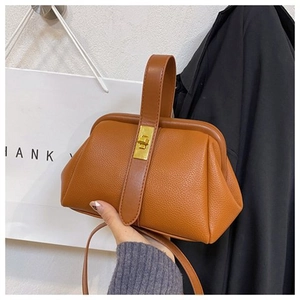Close-up of brown lychee texture shell bag with golden metal lock and top handle