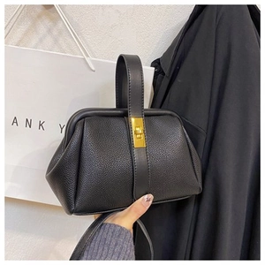 Detail of black lychee grain leather shell bag with elegant gold metal twist lock