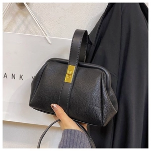 Close-up of black lychee grain leather shell bag with elegant gold metal twist lock