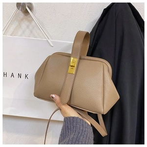 Close-up of pebble leather texture and gold metal twist-lock on a beige shell bag