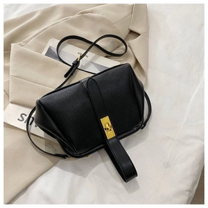 Close-up of black litchi pattern shell bag with gold clasp on chic urban background