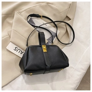 Close-up of black pebbled leather shell bag with golden metal lock and handle detail