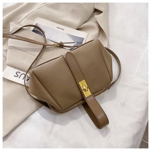 Detail view of coffee brown leather shell bag featuring lychee texture and gold twist lock