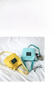 Detailed view of yellow and blue canvas mini bucket bags with shoulder straps and metal buttons