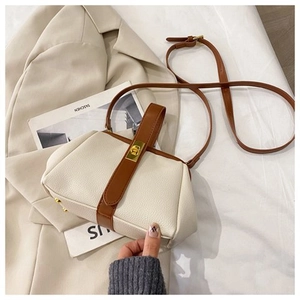 Detail of lychee pattern leather handbag with gold metal lock and brown leather trim