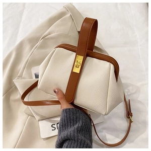 Detail of lychee pattern leather handbag with golden metal twist lock and brown handle