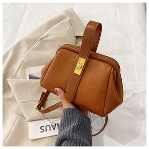 Detail of vintage brown textured frame bag with golden metal twist lock and lychee leather