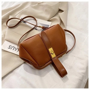 Macro detail of brown litchi pattern leather handbag with gold metal twist lock buckle