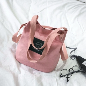 Pink canvas mini bucket tote bag with wide shoulder strap and woven letter label