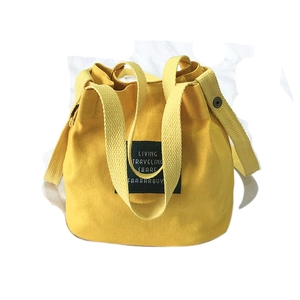 Mini yellow canvas bucket bag with black label and shoulder strap for casual travel