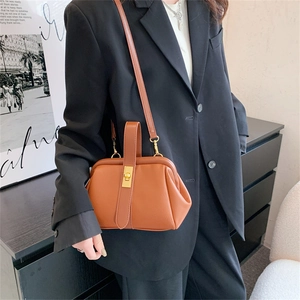 Classic brown leather shell bag with gold lock and vintage clasp, shown on a model