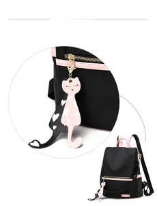 Détail de breloques en forme de chat sur un sac à dos en nylon noir avec bord rose
