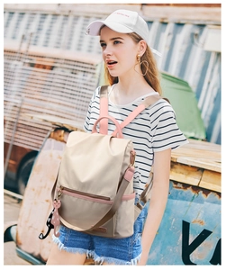 Sac à dos antivol en tissu oxford beige avec breloque chat porté par un mannequin
