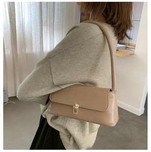 Détail du sac baguette kaki avec boucle en métal doré porté à l'épaule par le mannequin