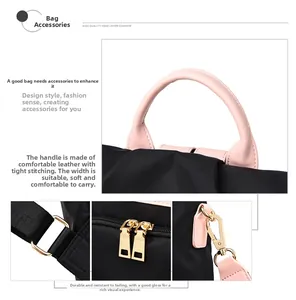 Détail de la poignée en cuir rose et zips dorés sur un sac à dos en tissu oxford noir