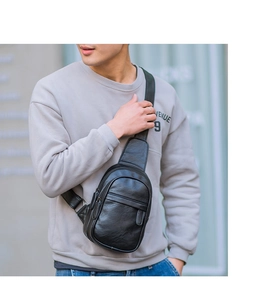 Model wearing black leather chest bag with zipper detail and adjustable strap for outdoors