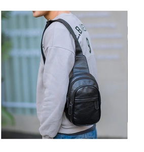 Rear view of model wearing black PU leather chest bag with sleek double zipper detail