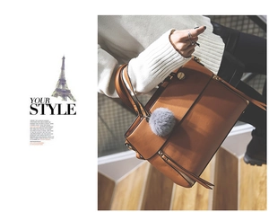 Detail of vintage brown leather tote bag with stylish pompom charm and zipper pockets