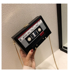 Macro detail of retro cassette tape shaped black box bag with golden chain and clasp