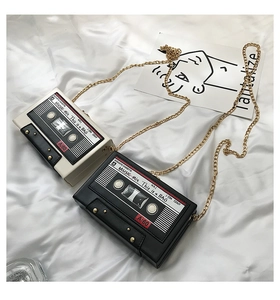 Close-up of retro cassette-shaped crossbody bags with chain straps in black and cream