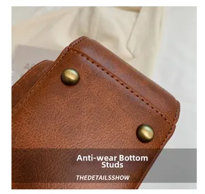 Detailed macro view of the vintage brown PU leather bag bottom with bronze protective studs