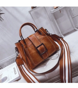 Detail of vintage caramel brown faux leather satchel with wide striped shoulder strap
