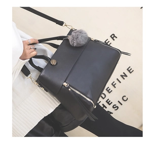 Close-up of black PU leather tote bag with gray fur ball charm and golden hardware