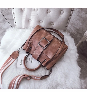 Close-up of vintage brown matte leather lady bag with metal buckle and striped strap