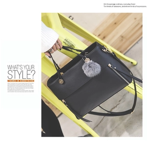 Detail of black faux leather tote with grey fur charm and gold hardware accents