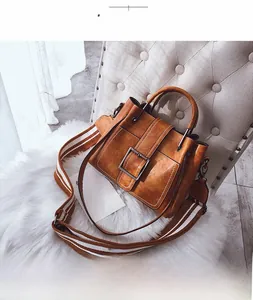 Detail view of vintage matte leather bag with a metal buckle and striped fabric strap