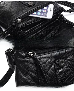 Close-up of smooth metal zippers and crinkled PU leather texture on the crossbody bag