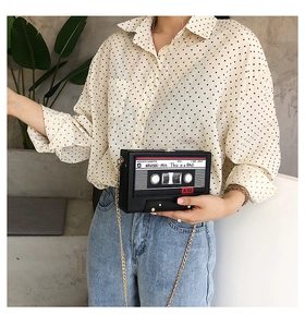 Detail of retro cassette tape shaped box bag featuring gold chain and music print design