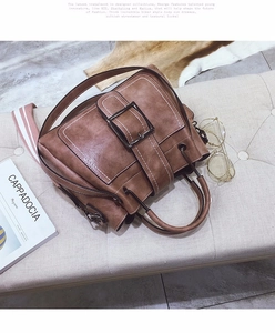 Detail of vintage brown frosted leather lady bag with modern striped woven shoulder strap