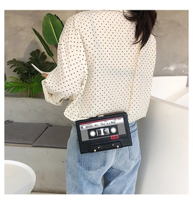 Detail of vintage cassette shape crossbody bag with gold chain strap on model