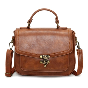 Detailed view of the brown leather texture and bronze vintage metal clasp on the square bag