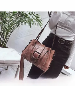 Detail of vintage matte leather bag with contrast stitching and metal buckle on model