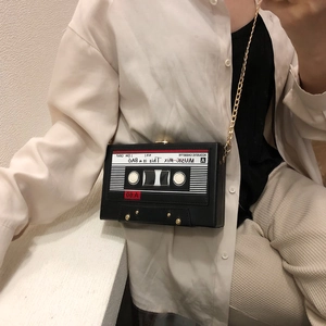 Close-up of vintage cassette-shaped crossbody bag with gold chain and music print